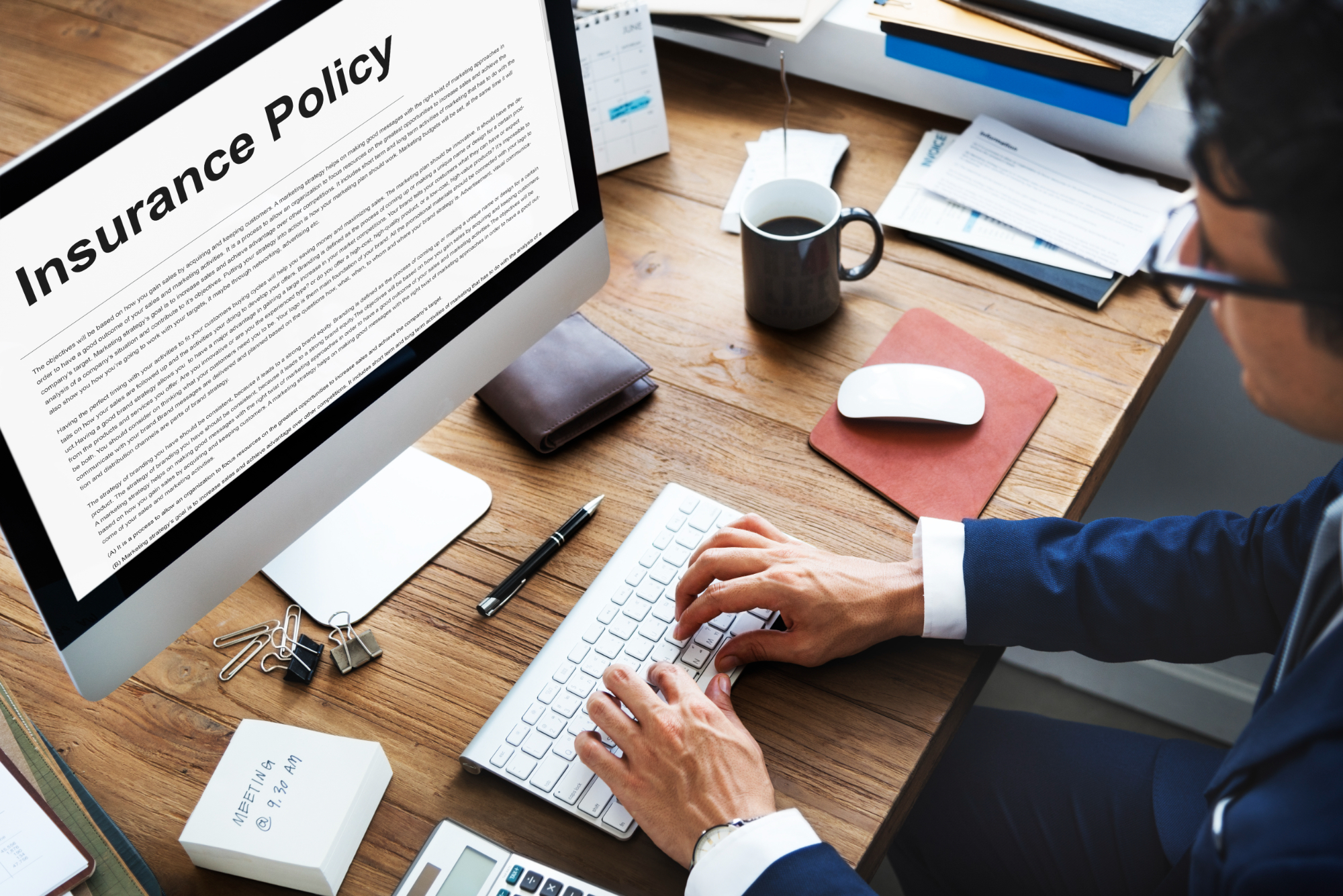 A person in business attire types on a keyboard at a desk, reviewing an insurance policy document with “Illnesses Covered By TPD” displayed on a large computer monitor. Office supplies, a phone, and a wallet are also on the wooden desk. A person in business attire types on a keyboard at a desk, reviewing an insurance policy document with "Illnesses Covered By TPD" displayed on a large computer monitor. Office supplies, a phone, and a wallet are also on the wooden desk.