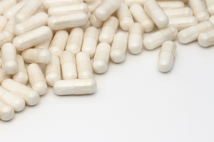 A pile of white capsules spread across a white surface, with some capsules separated from the group—an image highlighting issues that may relate to Medical Negligence Compensation.