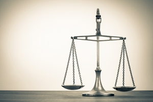 A silver balance scale stands on a wooden surface against a plain, light-colored background, symbolizing justice, fairness, and the importance of public liability. A silver balance scale stands on a wooden surface against a plain, light-colored background, symbolizing justice, fairness, and the importance of public liability.