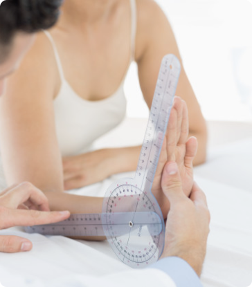 A person uses a transparent goniometer to measure the wrist angle of another person's extended hand, likely in a clinical or physical therapy setting.