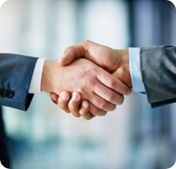 Two people in business suits shaking hands, symbolizing agreement or partnership, with a blurred office background.