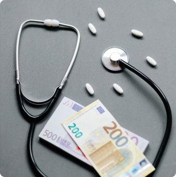 A stethoscope, several white pills, and euro banknotes are arranged on a gray surface, symbolizing the connection between healthcare and financial costs. A stethoscope, several white pills, and euro banknotes are arranged on a gray surface, symbolizing the connection between healthcare and financial costs.