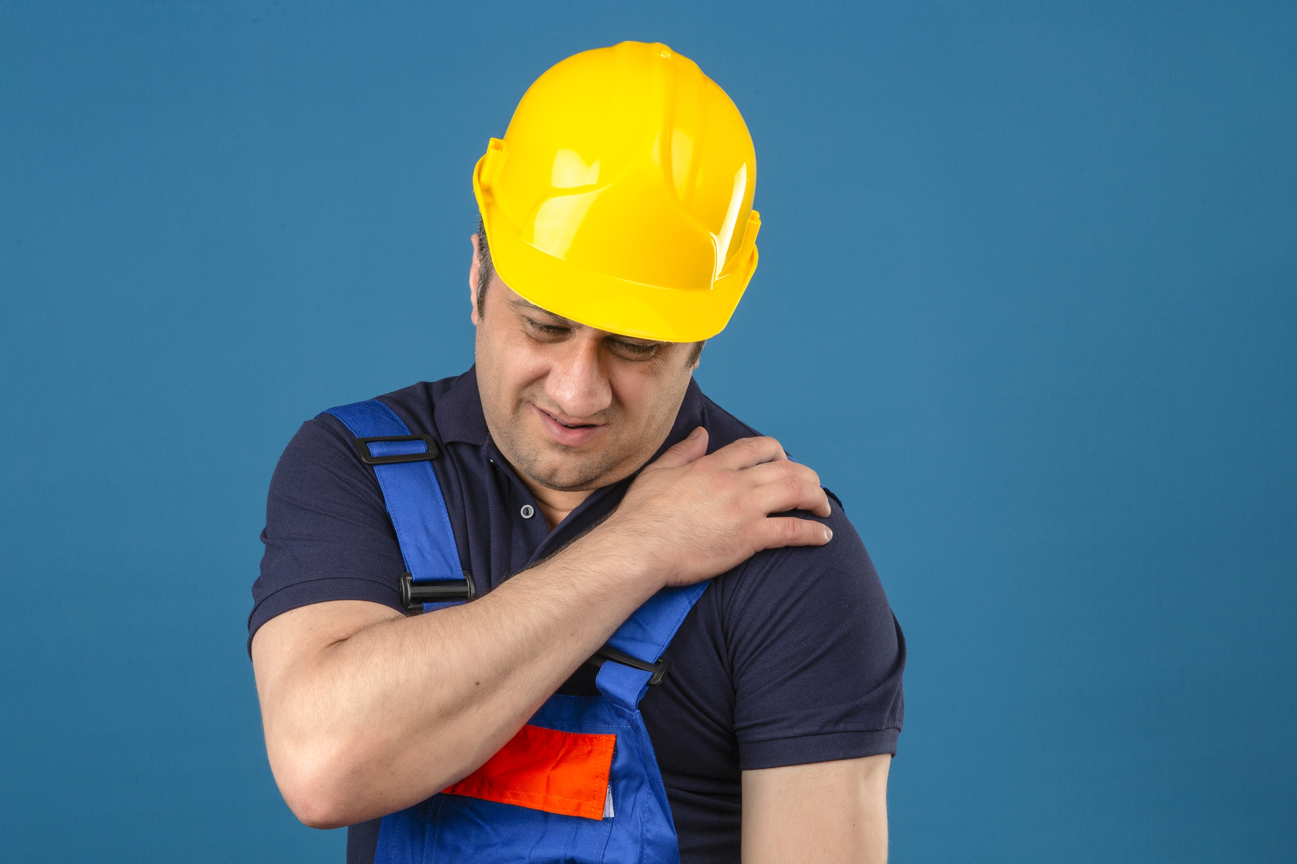constructor middle aged man wearing construction uniform and safety helmet touching shoulder having pain over isolated blue background constructor middle aged man wearing construction uniform and safety helmet touching shoulder having pain over isolated blue background